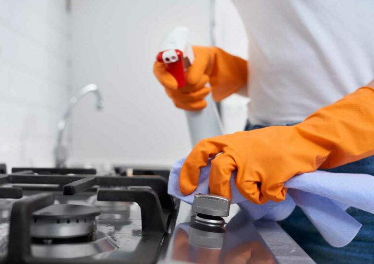 Personne lavant des feux à induction avec des gants et du produit pour garantir la sécurité alimentaire et respecter les normes HACCP