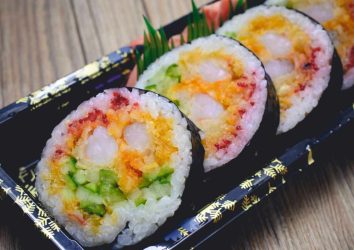 Trois tranches de Sushi Futomaki avec de carotte de l'avocat de la crevette et du choux rouge